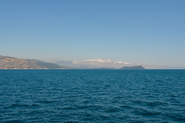 Obraz premium View of greek island against clear blue sky from ferry . Greece coastline . Summer vacation