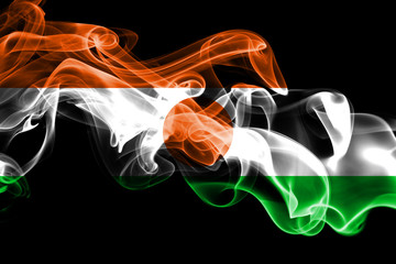 National flag of Niger made from colored smoke isolated on black background. Abstract silky wave background.