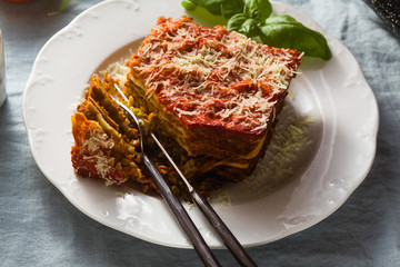 vegan lasagna with lentils and green peas in a baking sheet on a table with a blue linen...