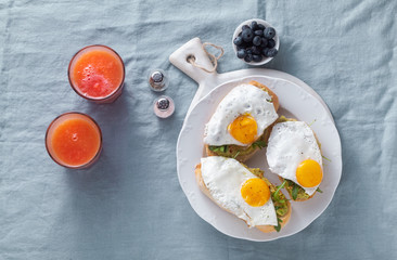 avocado sandwich and fried egg with paprika on the table. healthy breakfast or snack on a plate on a blue linen tablecloth and freshly squeezed grapefruit juice