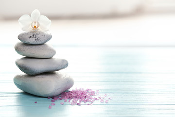 Spa stones, sea salt and flower on table against blurred background. Space for text