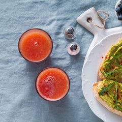 Avocado and arugula sandwich with paprika on the table. healthy breakfast or snack on a plate on a blue linen tablecloth and freshly squeezed grapefruit juice