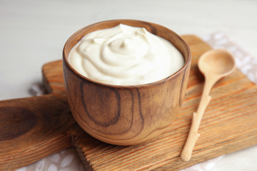 Wooden bowl with creamy yogurt served on table
