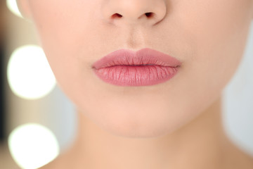 Young woman wearing beautiful lipstick on blurred background, closeup