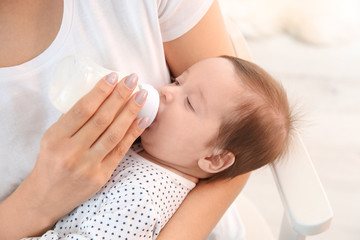 Obraz na płótnie Canvas Woman feeding her baby from bottle at home, closeup
