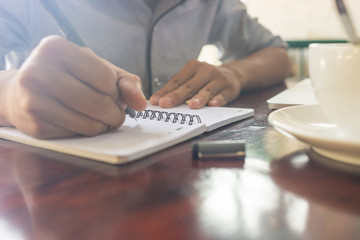 Young man hand writing note on a notebook
