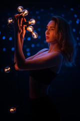 A beautiful girl with stars, and holding a light bulb. Warm and cold light. Artistic Photography