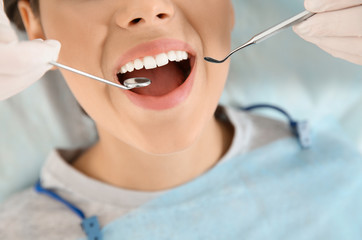 Dentist examining patient's teeth in modern clinic, closeup