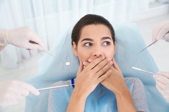 Young woman scared of dental examination in clinic