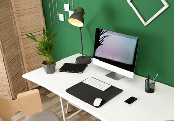 Stylish workplace with modern computer near color wall. Space for text