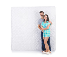 Young couple with comfortable mattress isolated on white