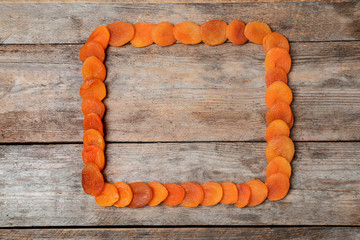 Frame made of apricots on wooden background, top view with space for text. Dried fruit as healthy food