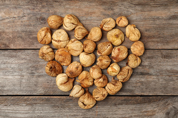 Heart made of figs on wooden background, top view. Dried fruit as healthy food