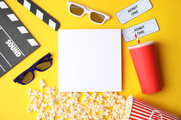 Flat lay composition with blank paper, popcorn and clapper on color background, mockup for design. Watching cinema