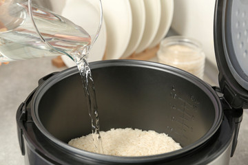 Fototapeta na wymiar Water pouring into modern rice cooker in kitchen