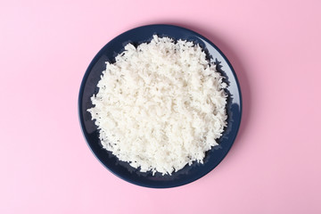 Plate of boiled rice on color background, top view