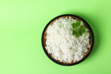 Bowl of boiled rice on color background, top view with space for text