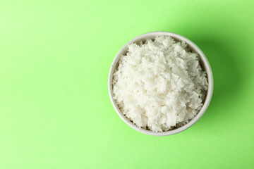 Bowl of boiled rice on color background, top view with space for text