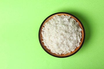 Bowl of boiled rice on color background, top view with space for text