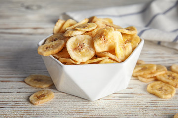 Bowl with sweet banana slices on wooden  table. Dried fruit as healthy snack