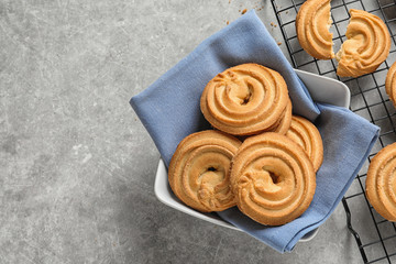 Bowl and baking rack with Danish butter cookies on grey table, top view. Space for text