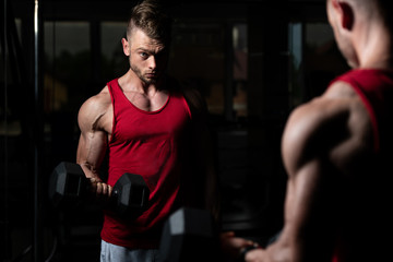 Bodybuilder Exercising Biceps With Dumbbells