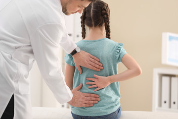 Chiropractor examining child with back pain in clinic