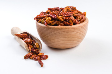 piri piri pepper in wooden bowl and scoop isolated on white background. Closeup.