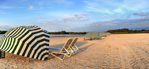 Beach umbrella cabanas over folding chairs along the white sand of Tigertail Beach in Marco Island