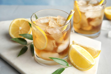 Glass of lemonade with ice cubes and fruit on table