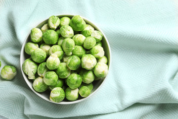 Bowl of fresh Brussels sprouts on fabric, top view with space for text