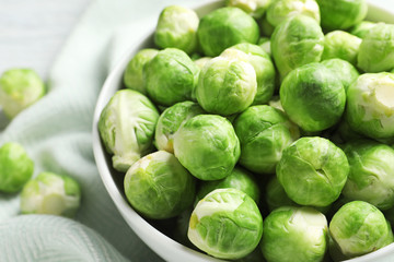 Bowl of fresh Brussels sprouts on fabric, closeup