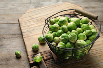 Metal basket with fresh Brussels sprouts on wooden table. Space for text