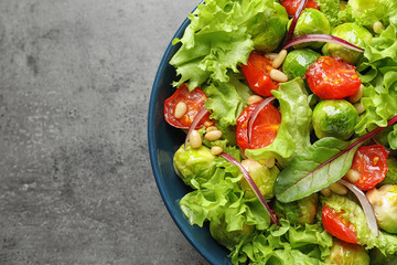 Bowl of salad with Brussels sprouts on grey background, top view. Space for text