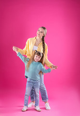 Obraz na płótnie Canvas Happy woman and daughter in stylish clothes on color background