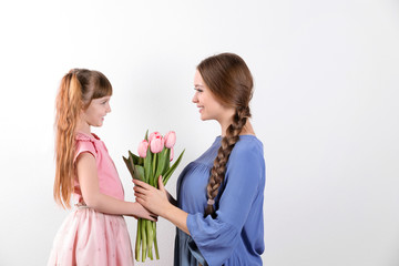 Happy mother and daughter with flower bouquet on white background. International Women's Day