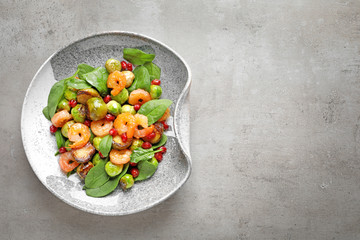 Plate of warm salad with Brussels sprouts on grey table, top view. Space for text