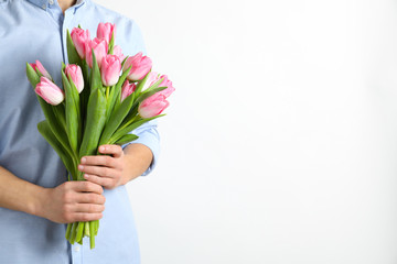 Man holding bouquet of beautiful spring tulips on light background, closeup. International Women's Day