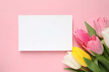 Beautiful spring tulips and card on color background, top view with space for text. International Women's Day