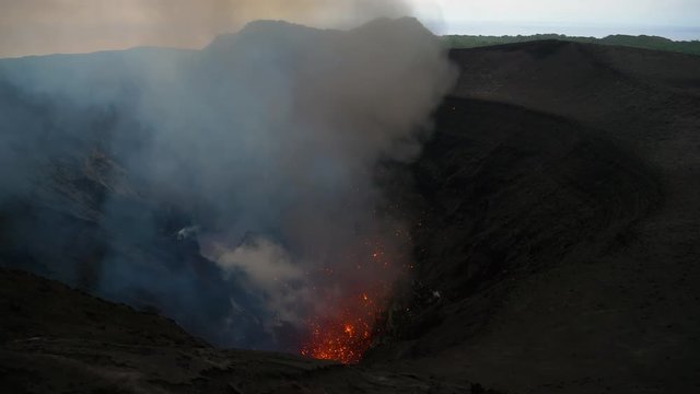 Breathtaking view from above of the roaring depths of an active volcano in Tanna. Stunning shot of Mount Yasur spewing out glowing lava high in the air. Volcanic crater erupting and emitting lava