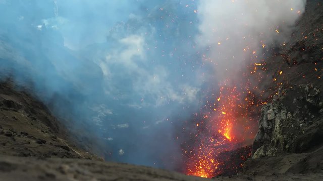 CLOSE UP: Roaring active volcano blasting out the glowing lava out of its depths. Volcanic crater erupting violently and emitting bright orange lava. Breathtaking shot of the depths of Mount Yasur.