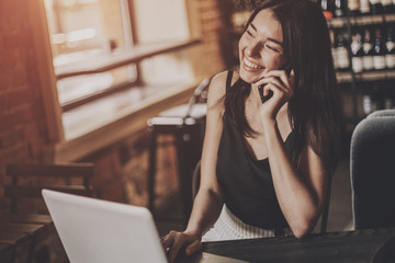 Business woman working on a laptop and using phone in a cafe.