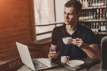 Businessman working on a laptop and using phone in a cafe.