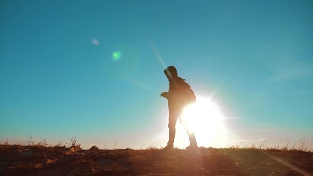 Male man lifestyle walking worth it tourist with backpack sunlight adventure stands on top of a mountain . slow motion video. man silhouette at sunset . hikers adventure and the go . travel silhouette