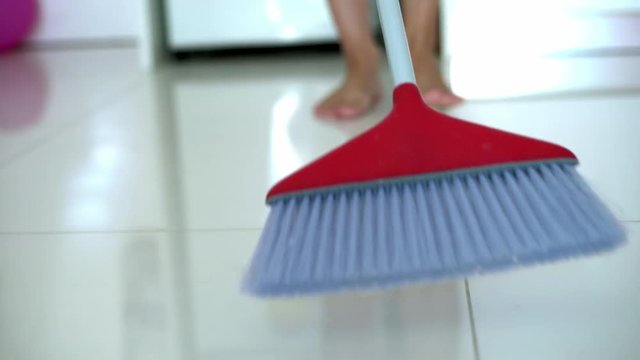 people, housework and housekeeping concept - woman with broom cleaning floor at home