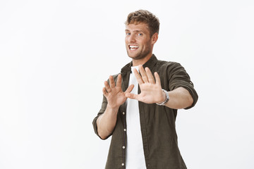 Guy nervously chuckling and tilting backwards with awkward worried smile, extending hands in...
