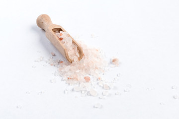 Himalayan pink salt  in wooden scoop isolated on white background. Closeup.