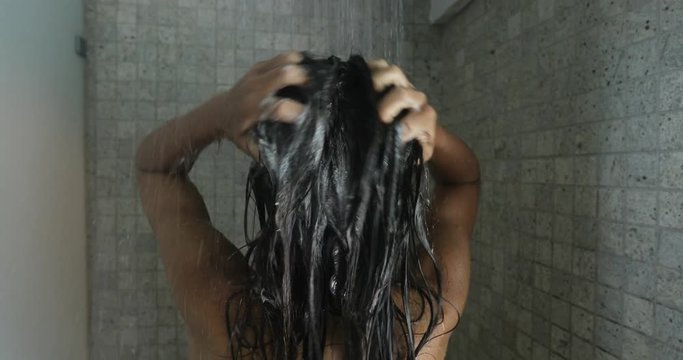 Woman washing hair with a shampoo taking shower. Young beautiful woman taking a shower and washing her hair with a shampoo. Beauty and wellbeing concept.