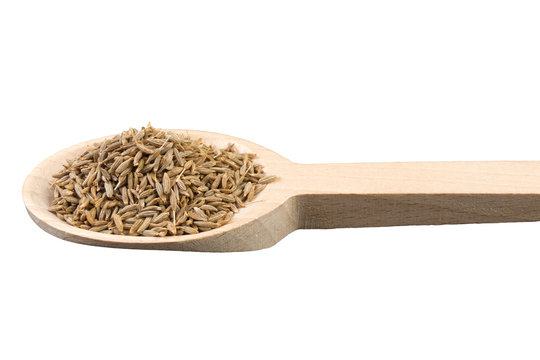 cumin in wooden spoon isolated on white background. Closeup.