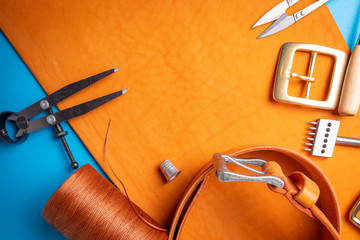 Working process of creating the leather belt in the leather workshop. Crafting tool, accessories, buckle and thread. Tannery atelier background.
